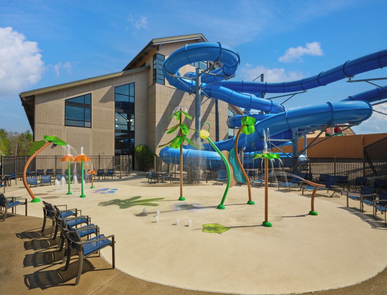 A water park with multiple slides and water features, seating areas, and a building in the background.