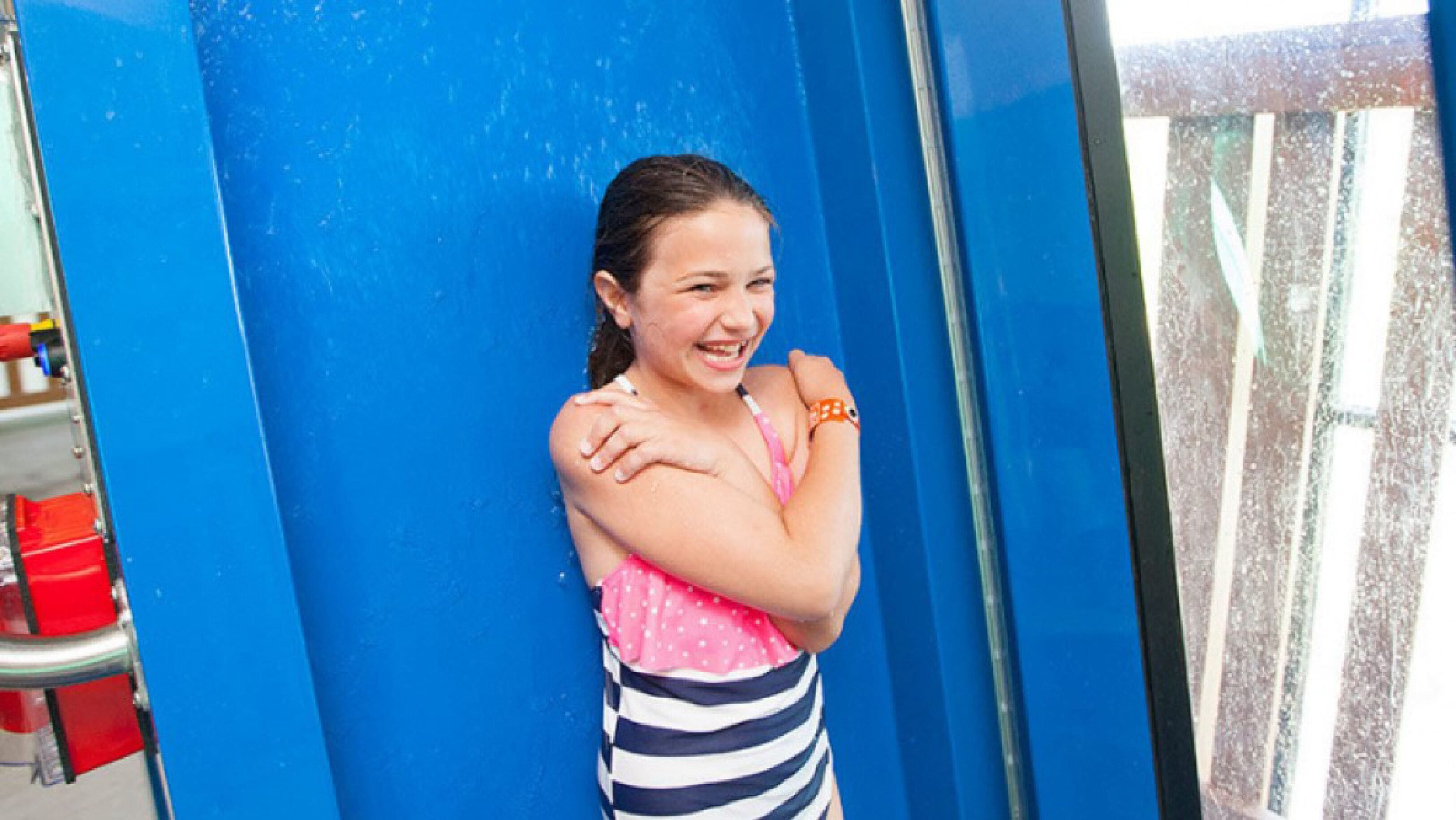 Una persona apoyada en una pared azul.