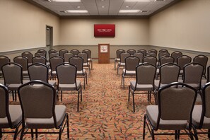 Ein Konferenzraum mit Reihen von Stühlen, einem Teppichboden und einem Rednerpult mit dem Logo von Great Wolf Lodge.