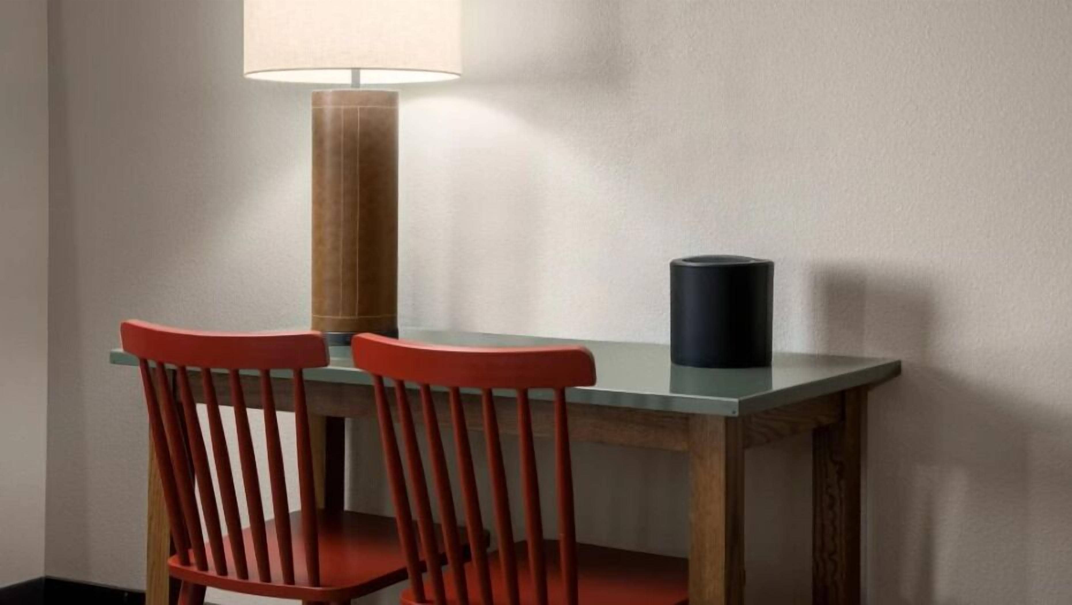 A table with two chairs, a lamp, and a cylindrical object on the table.
