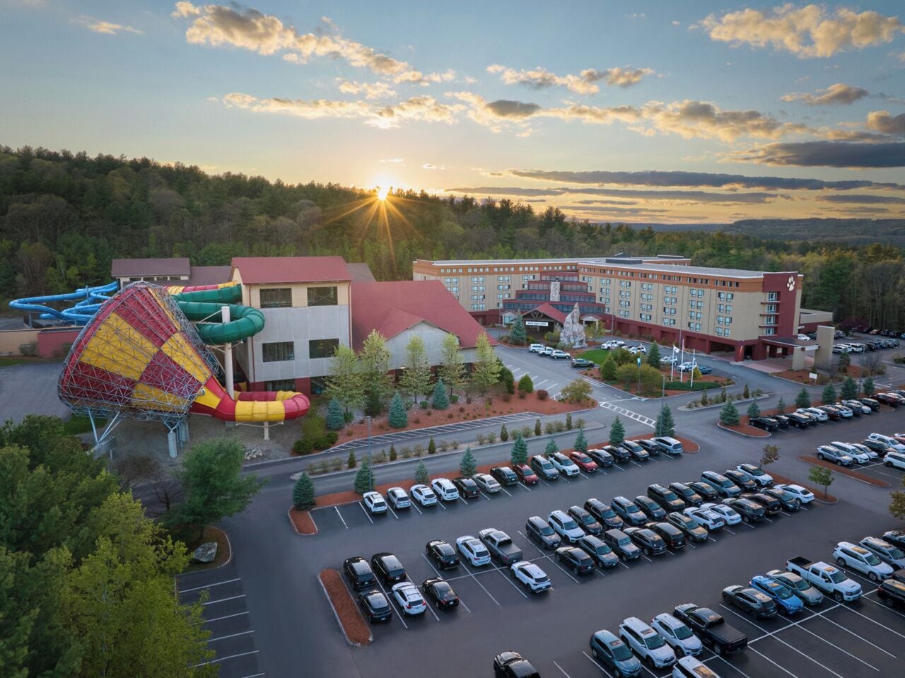 A hotel with a parking lot, a playground, and a building with a red roof.