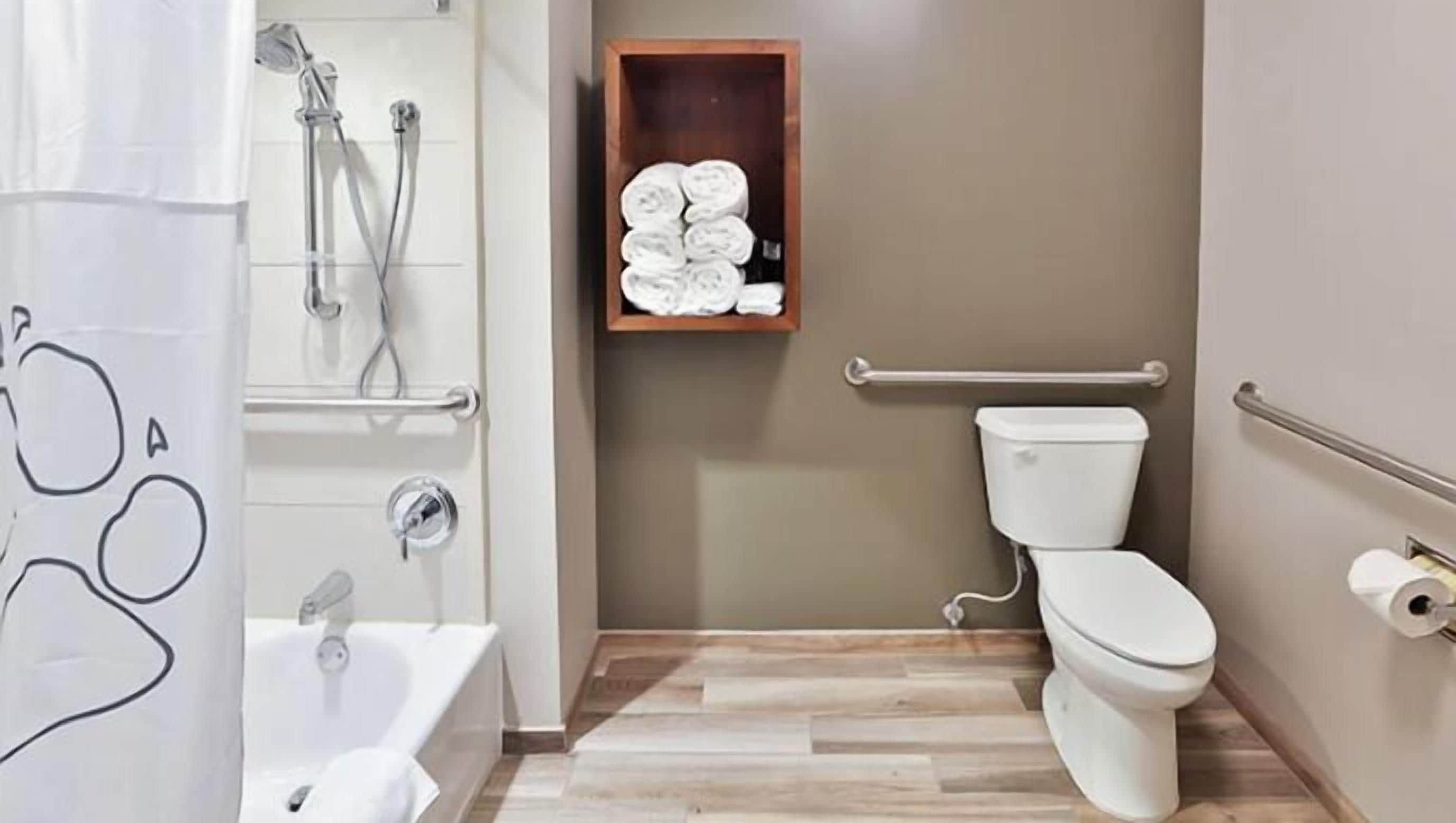 Une salle de bain avec une douche, des toilettes et une étagère avec des serviettes.