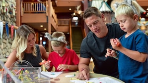 A group of people engaged in a craft activity at a table with various colored markers and papers.