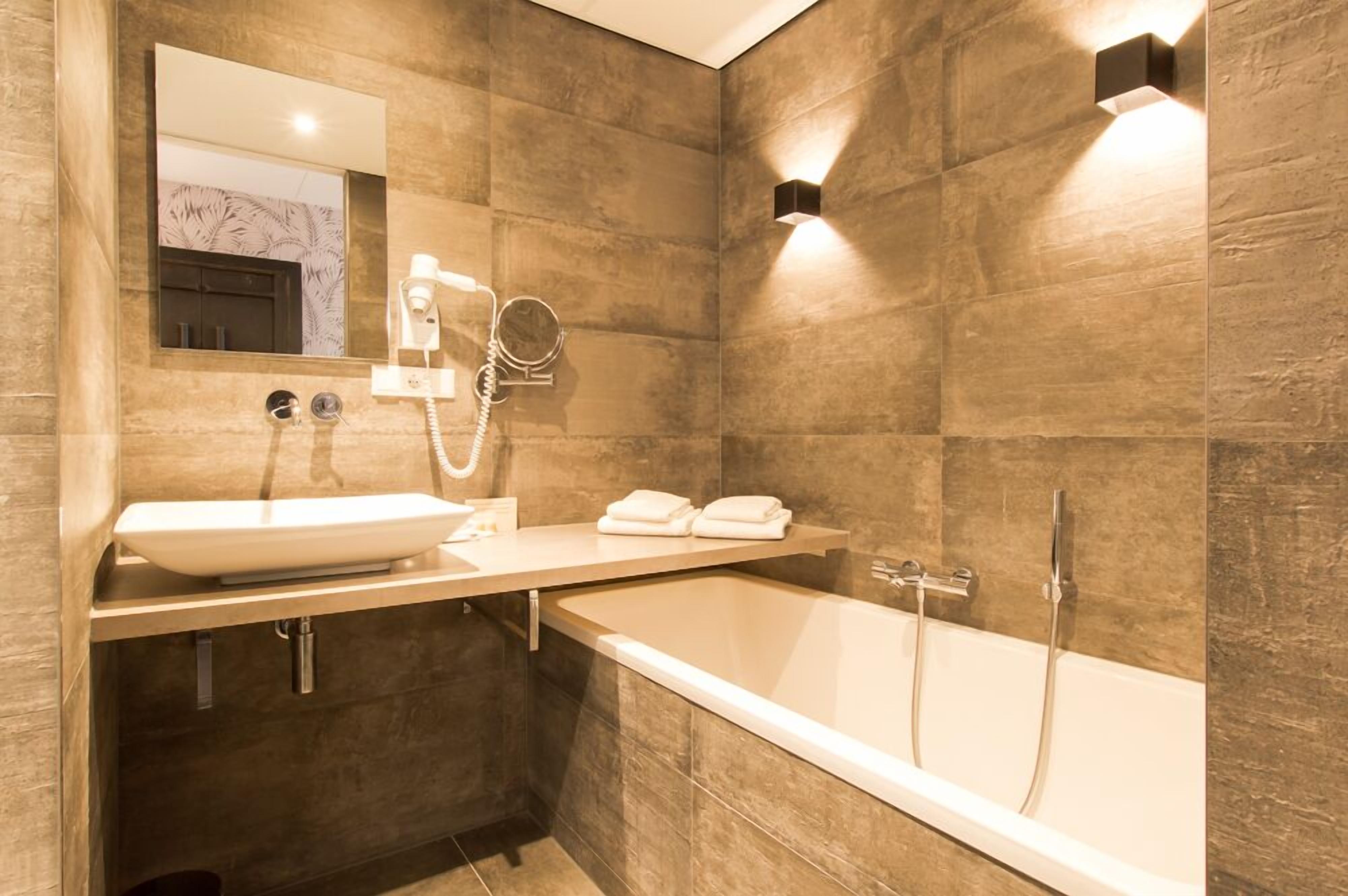 Un baño moderno con una bañera grande, un lavabo, un espejo y un perchero para toallas.