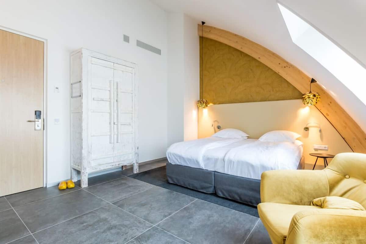 Quarto com cama, guarda-roupa, cadeira e claraboia.