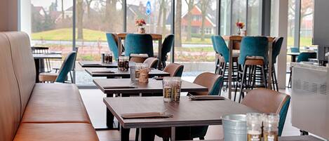 Un restaurante con mesas y sillas de madera, un banco y vistas al exterior.