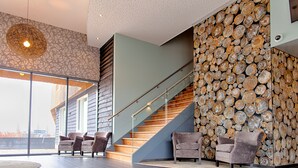 Un interior moderno con una escalera, una zona de estar y una pared de troncos.