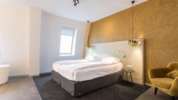 Ein modernes Schlafzimmer mit Bett, Nachttisch, Lampe und einem Sessel.