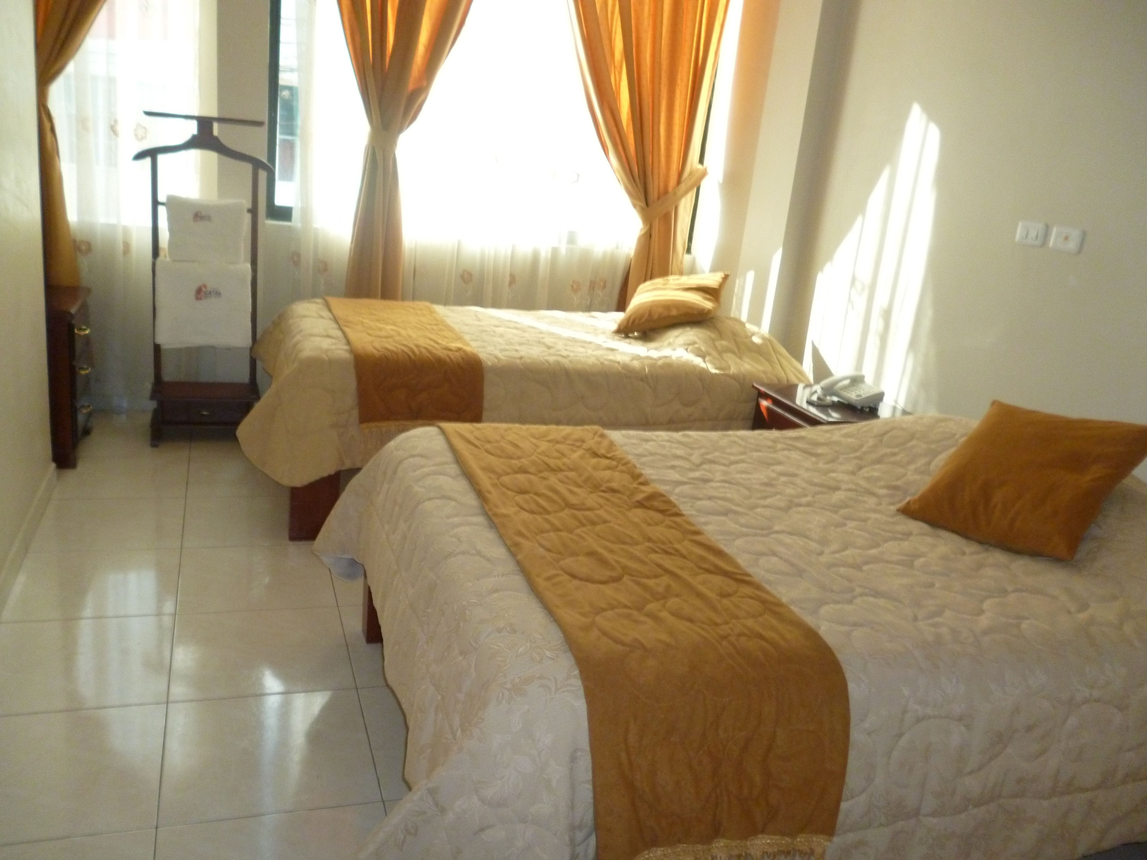 Two single beds with beige and brown bedding, a wooden wardrobe, and a small table with a telephone.