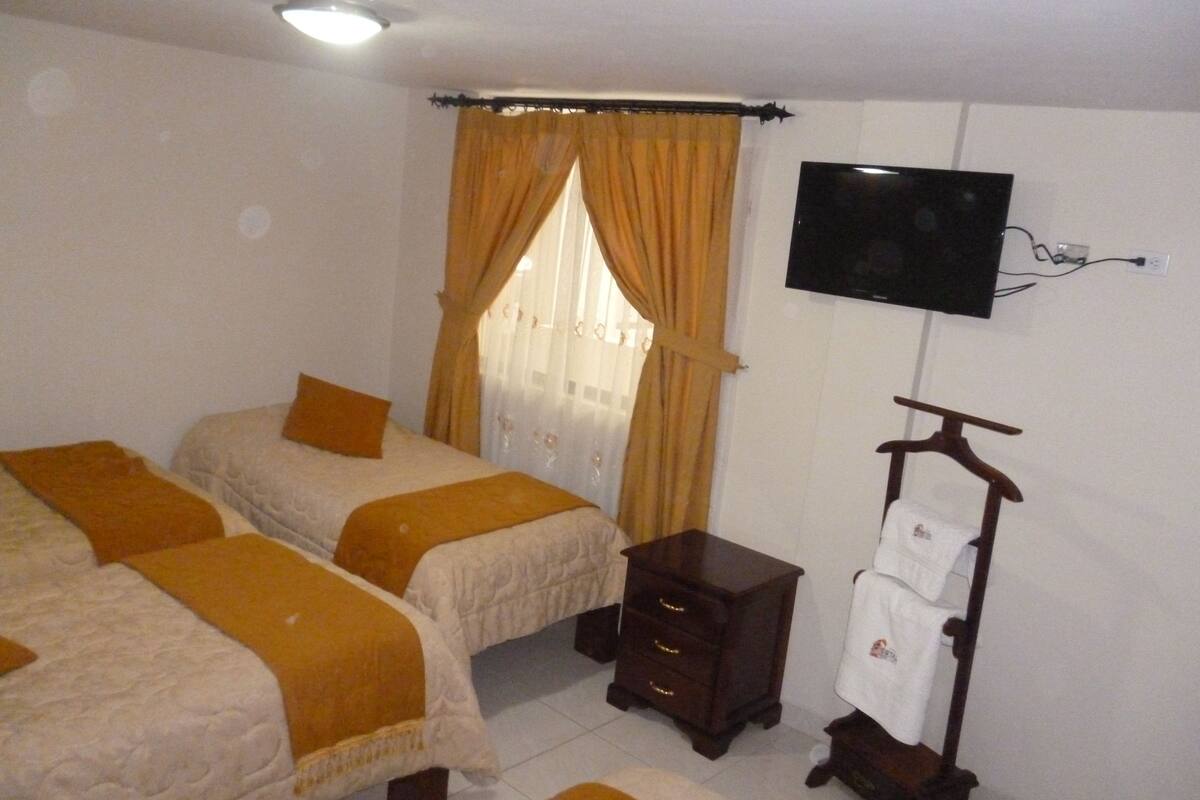 A bedroom with two beds, a TV mounted on the wall, and a wooden dresser.