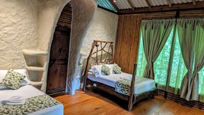 Un dormitorio rústico con una cama de madera, un banco de piedra y un amplio arco de entrada.