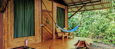 A wooden cabin with a porch, a hammock, and a fire extinguisher.
