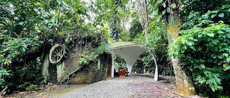 A natural stone archway leading into a forested area with a gravel path.