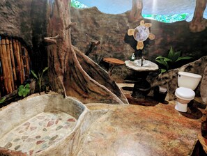 A bathroom with a stone sink, a toilet, and a small basin.
