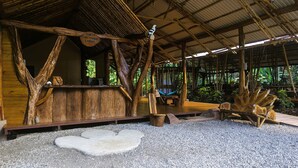 Un refugio rústico de estructura de madera, con una hamaca y una piedra con forma de corazón en el centro.