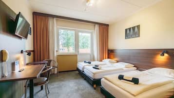Camera d'albergo con due letti, una scrivania, una sedia, televisore e una finestra con tende.