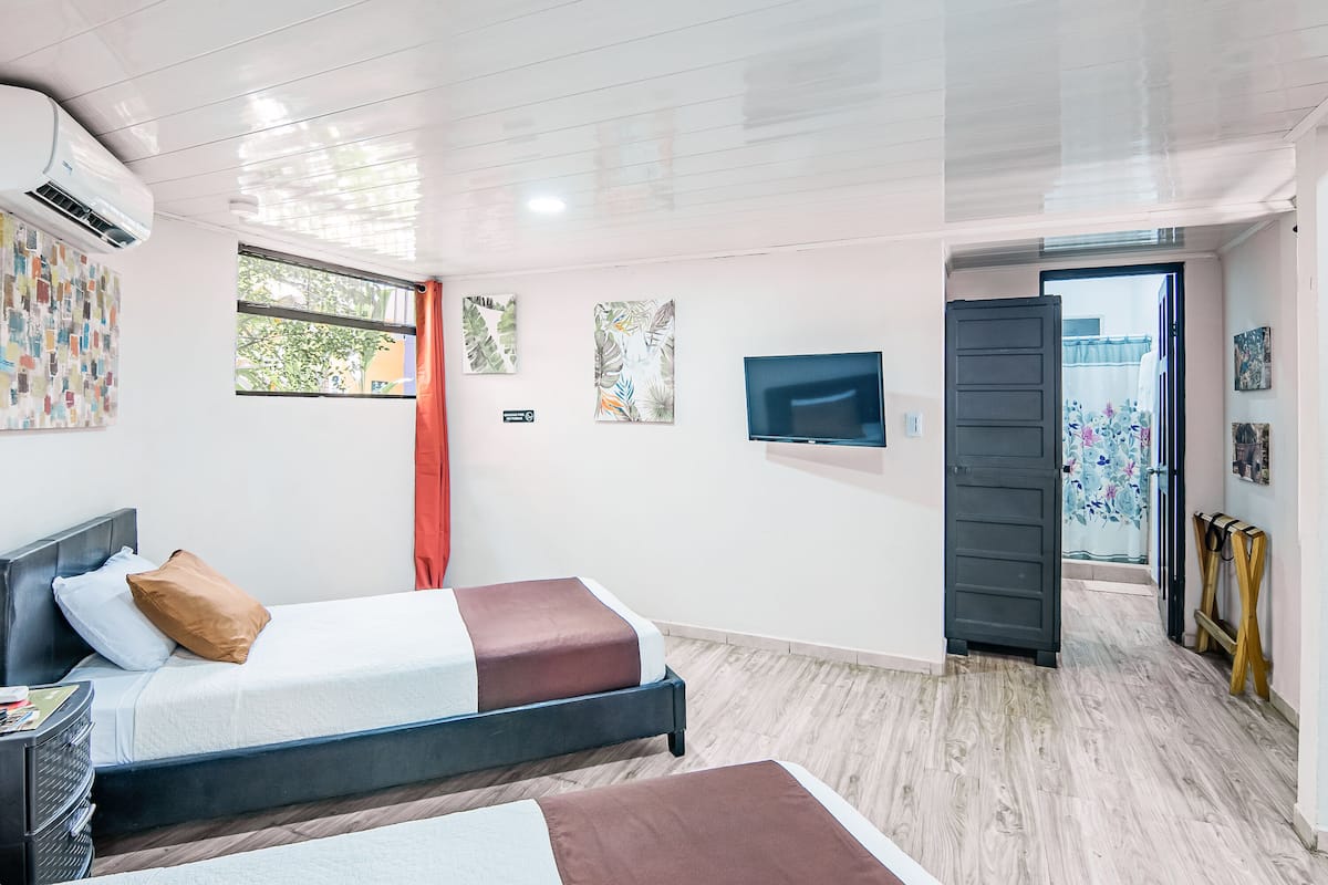 A modern hotel room with a bed, a TV, and artwork on the walls.