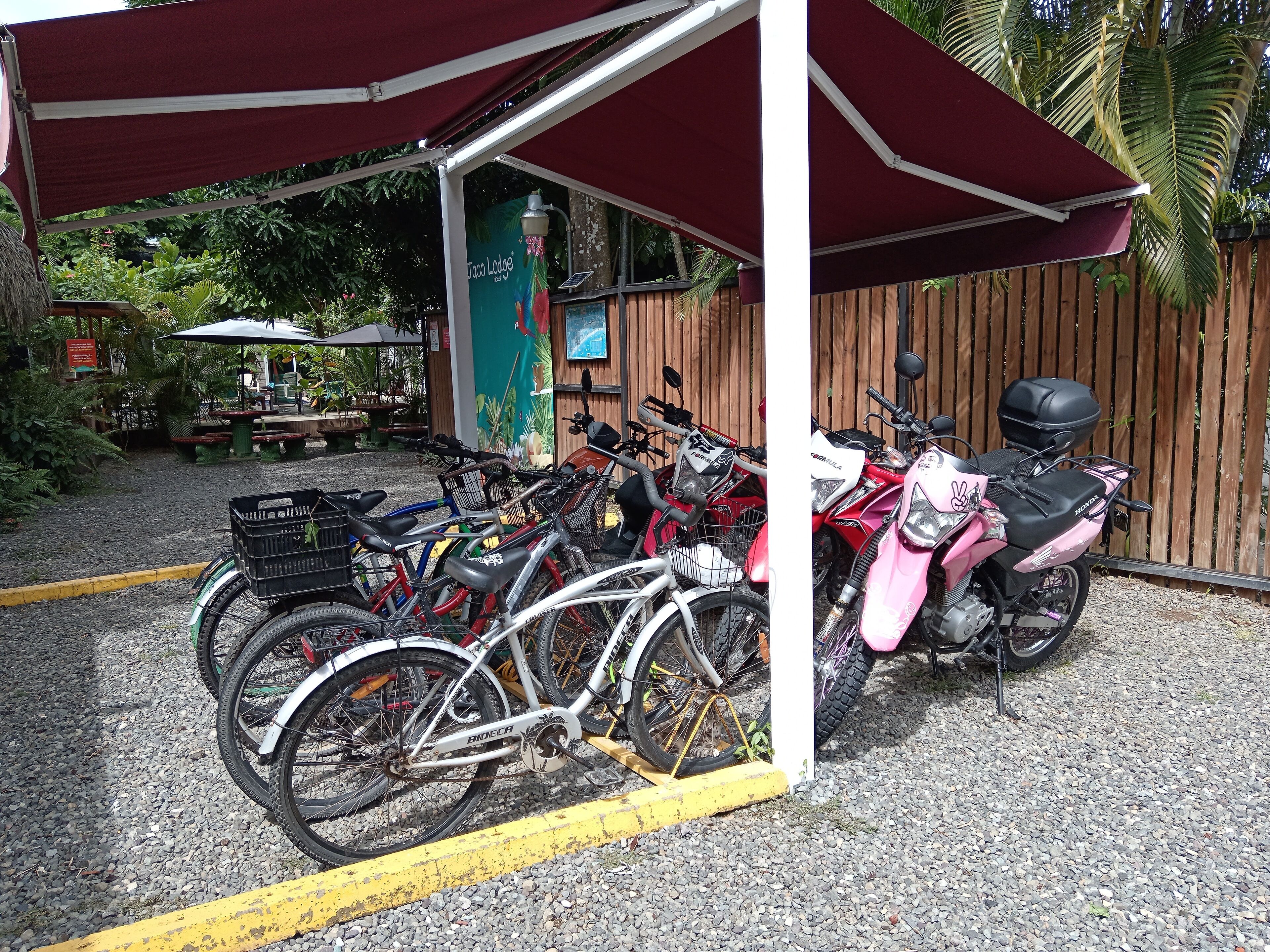 A covered parking area with bicycles and a motorcycle.