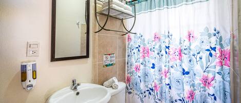 A bathroom with a sink, toilet, and a shower curtain with floral patterns.