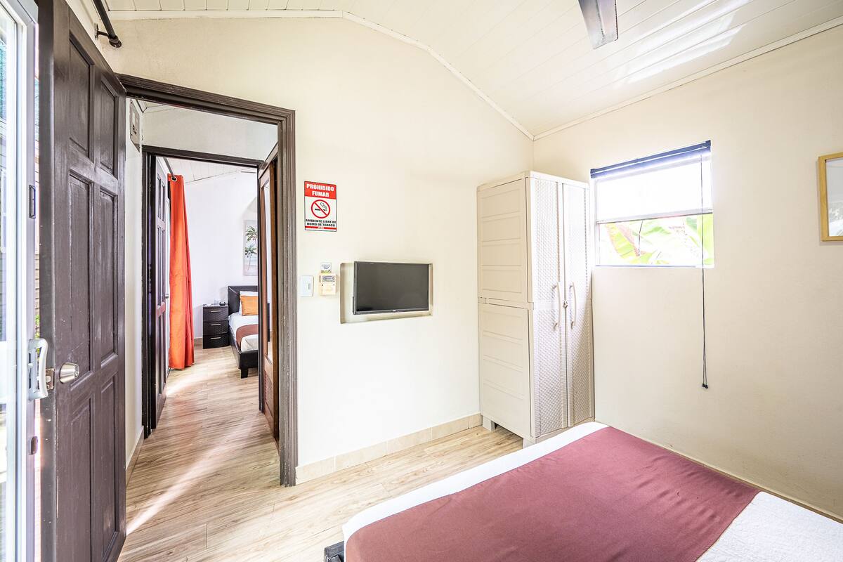 A hotel room with a bed, a TV, a wardrobe, and a bathroom with a shower curtain.
