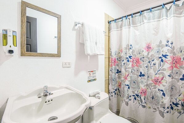 A bathroom with a sink, a mirror, a shower curtain with floral patterns, and a towel hanging on the wall.