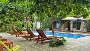 Ein Poolbereich mit Holzliegen, einem kleinen Pool und umgebender Bepflanzung.