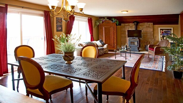 A dining area with a table and chairs, a fireplace, a television, and a sofa in a cozy living room.