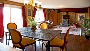 A dining area with a table and chairs, a fireplace, a television, and a sofa in a cozy living room. - B & B Tekdiv (Leeds and the Thousand Islands)