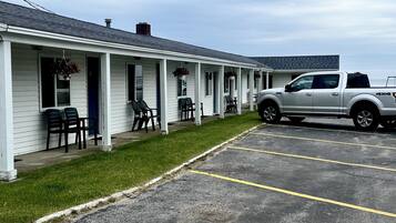 A motel with a row of rooms, each with a porch and outdoor seating.