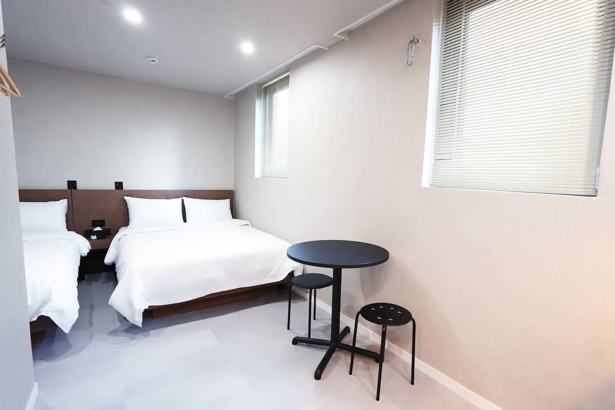 A bedroom with a bed, bedside tables, a round table, and a chair.
