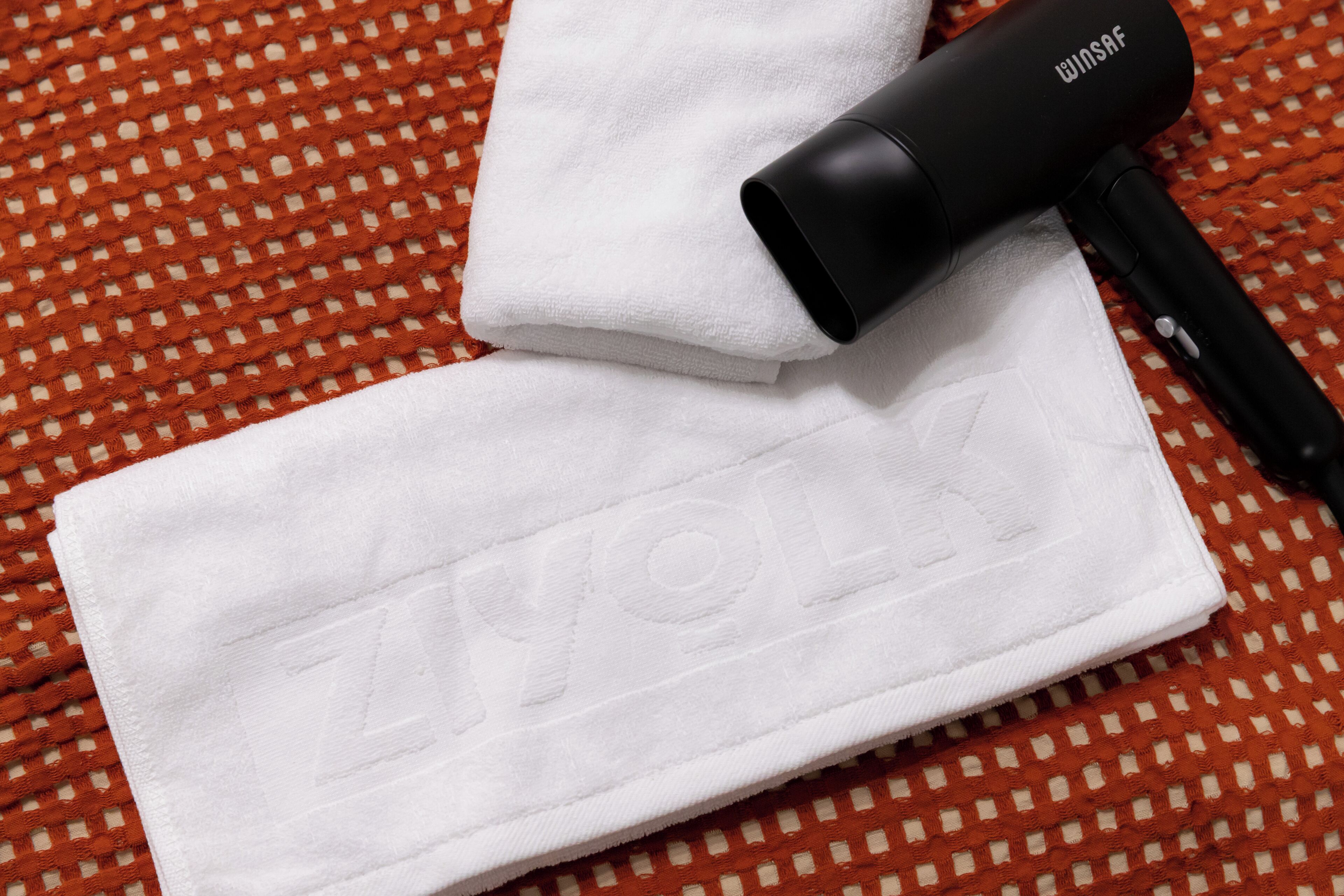 A white towel with the word "ZYLON" embossed on it, placed on a patterned orange and white surface.