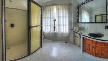A bathroom with a shower, toilet, sink, and mirror.