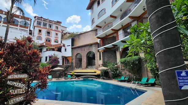 Una piscina con sillones de descanso, un restaurante y un cartel con los horarios de atención.