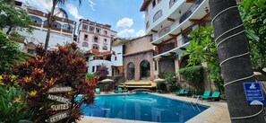 Relax by the serene pool surrounded by lush greenery and lounge chairs.