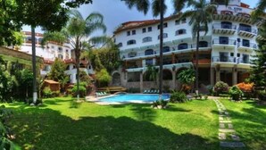 Un hotel con piscina rodeado de exuberante vegetación y palmeras.