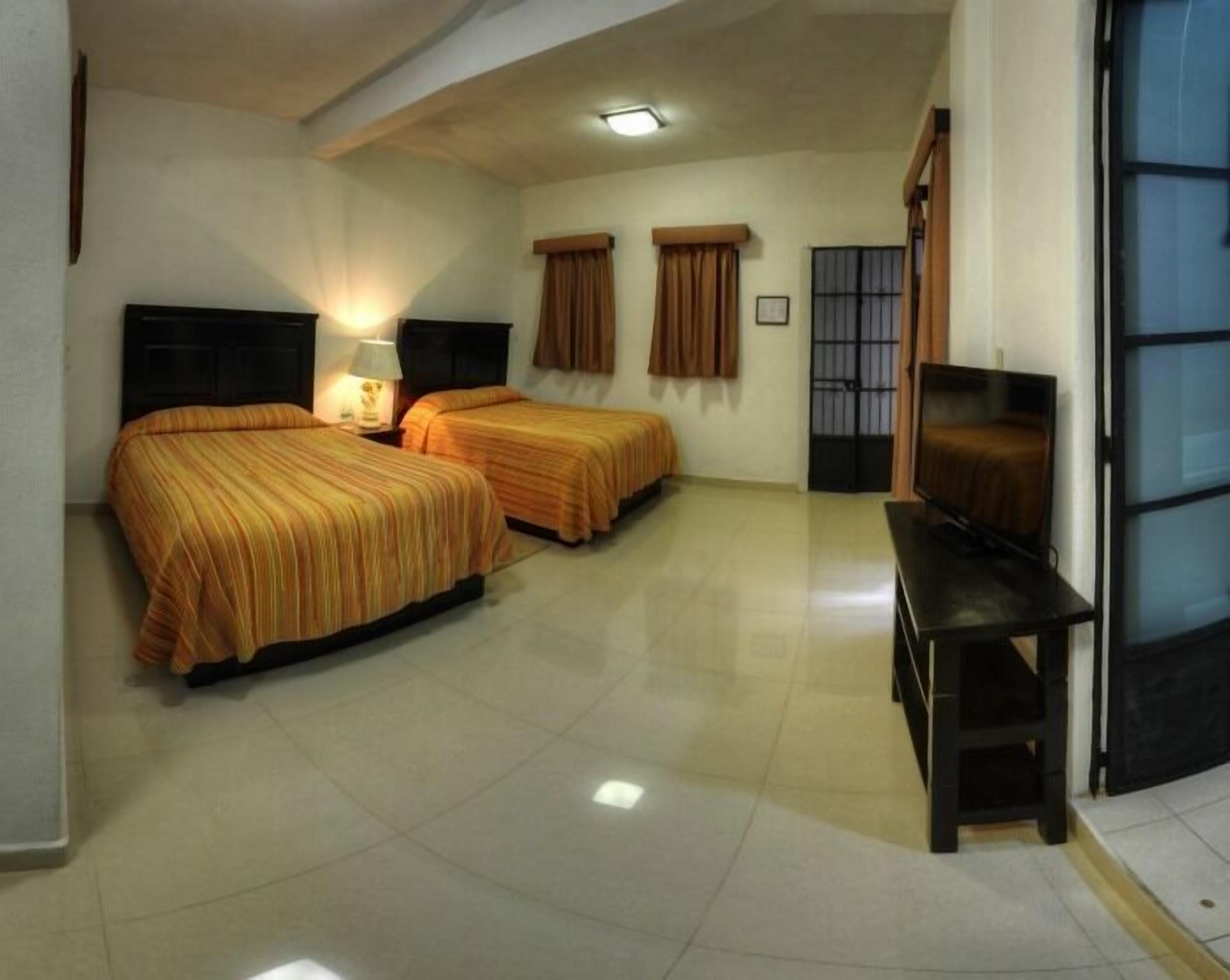 Una habitación de hotel con dos camas, televisión y escritorio.