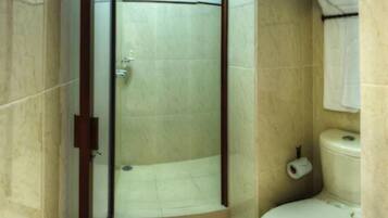 A bathroom with a shower, toilet, and a towel hanging on the wall.