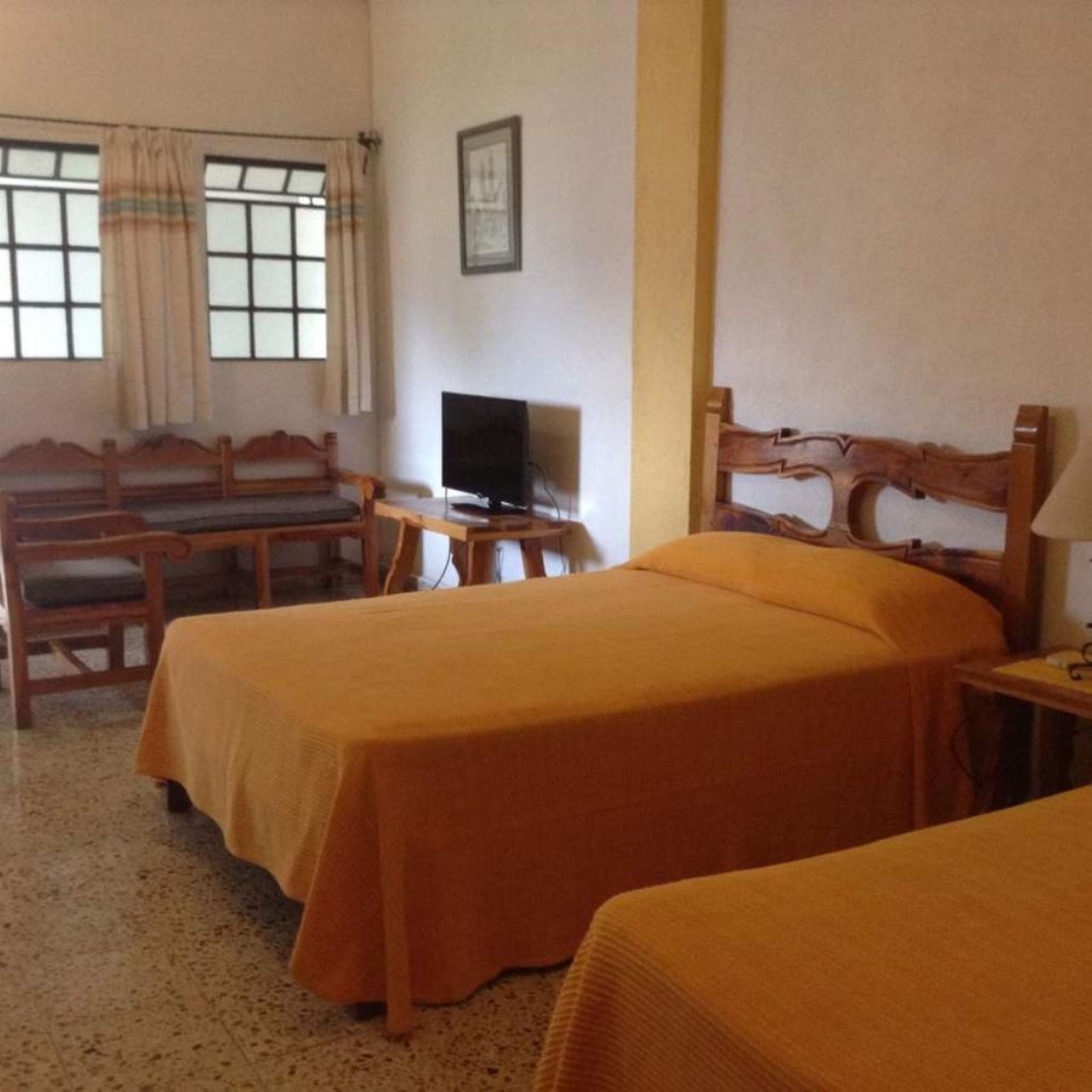 Una habitación con dos camas, un escritorio, una silla, un televisor y una ventana con cortinas.