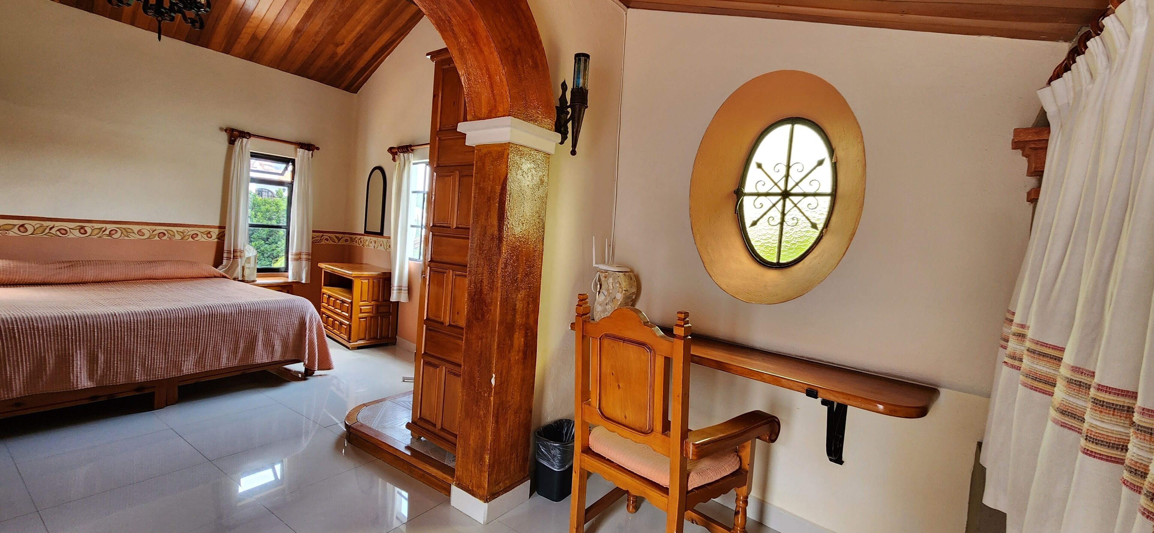 Un dormitorio con cama, un escritorio de madera, una silla, una ventana y una puerta.