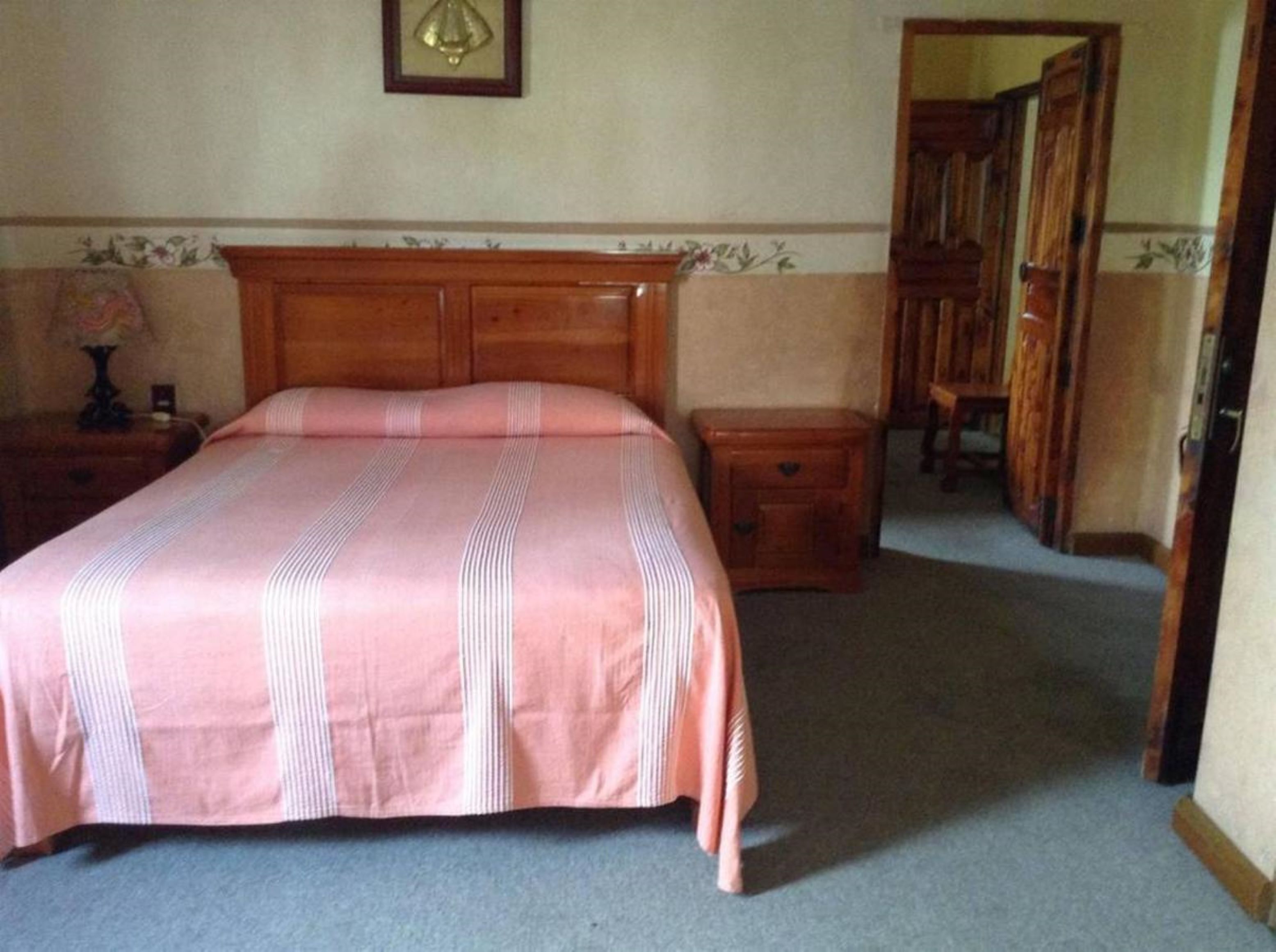 A bedroom with a wooden bed, a nightstand, a dresser, and a mirror.