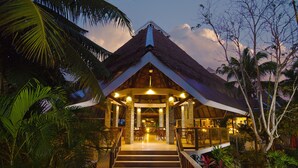 A resort with a thatched roof, a covered outdoor seating area, and lush tropical vegetation. - Mithi Resort & Spa (Dauis)
