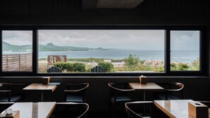 A restaurant with a view of the sea, featuring wooden tables and chairs. - The Light Inn (Hengchun)