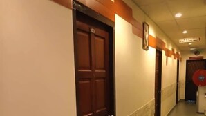 Un pasillo con puertas, un extintor y un reloj en la pared.