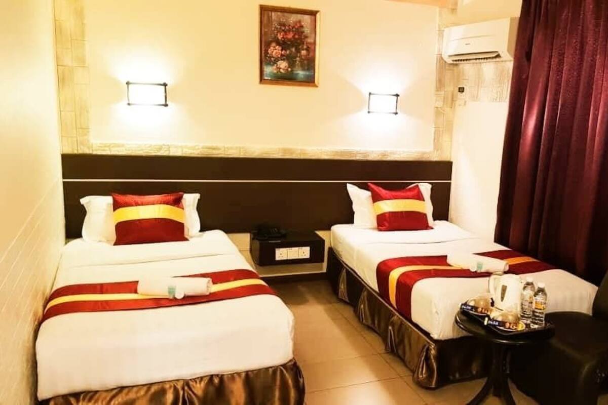 A hotel room with two beds, a small table with toiletries, and a chair.