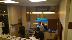 Zona de recepción con mostrador, un reloj y señalización de área de salida.