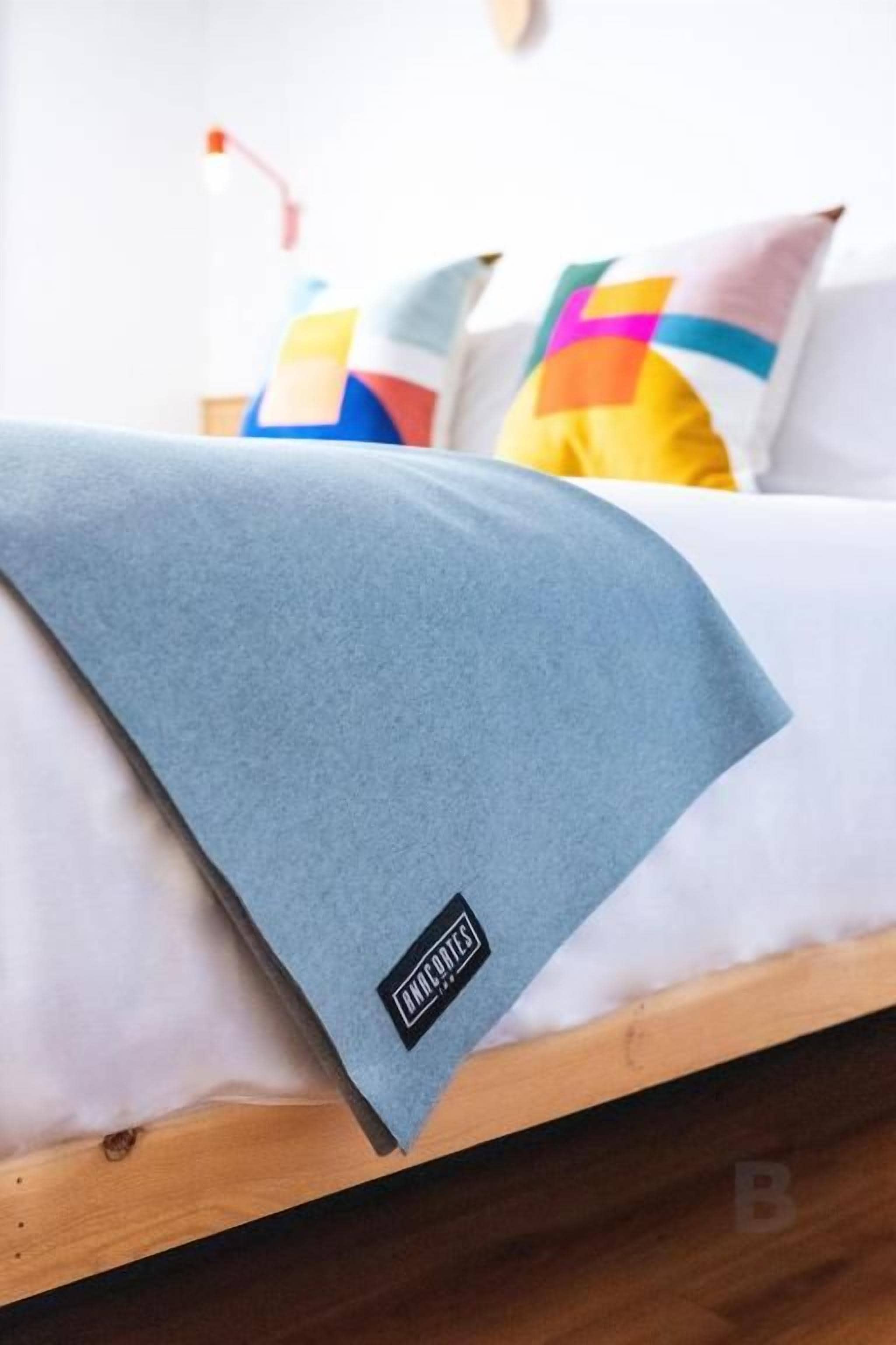 Ein Bett mit einer blauen Decke und einem Kissen mit geometrischem Muster.