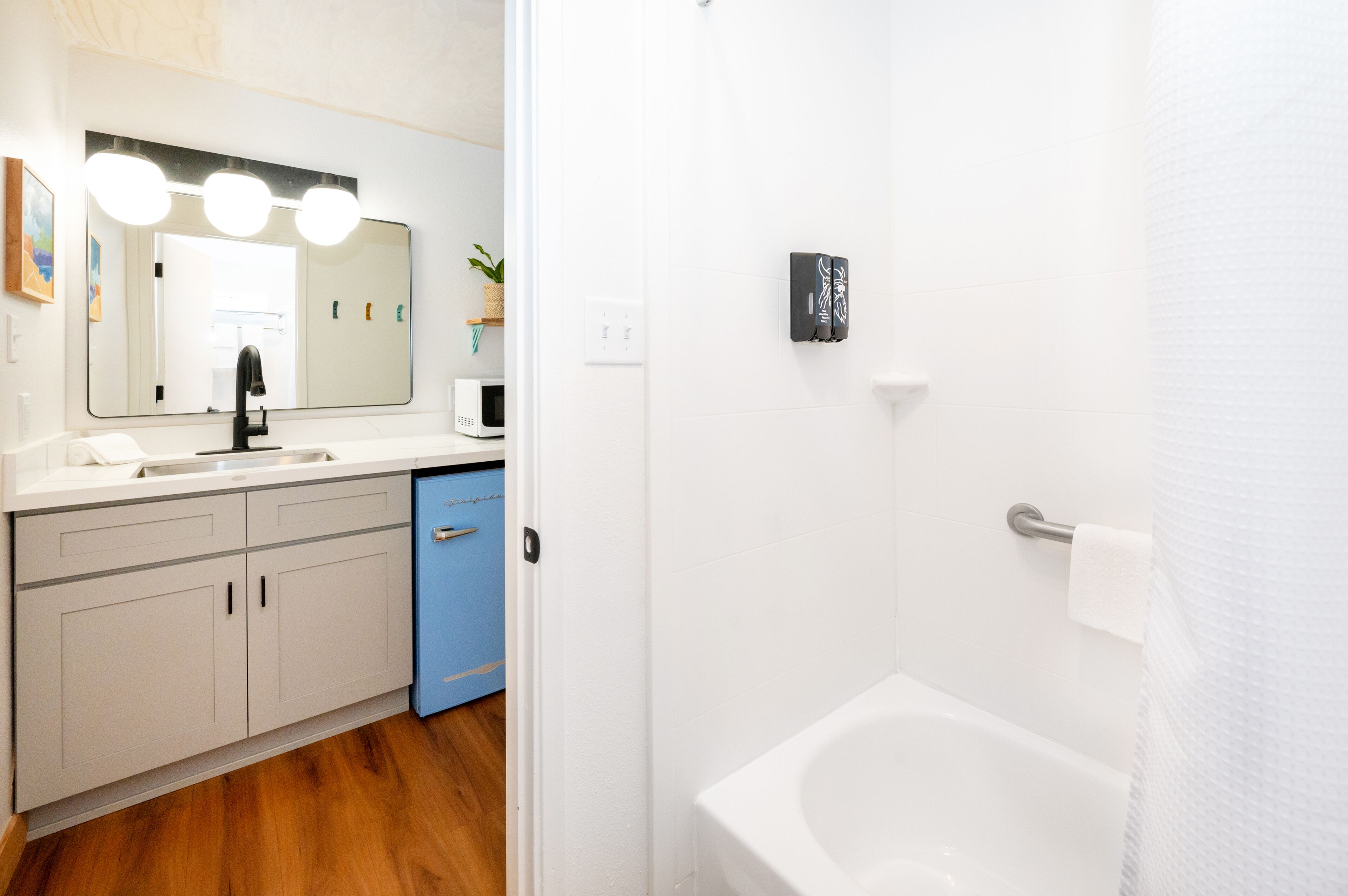 Une salle de bain avec un lavabo blanc, un miroir et une baignoire.