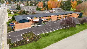 A hotel with a parking lot, a covered entrance, and a view of the surrounding neighborhood.