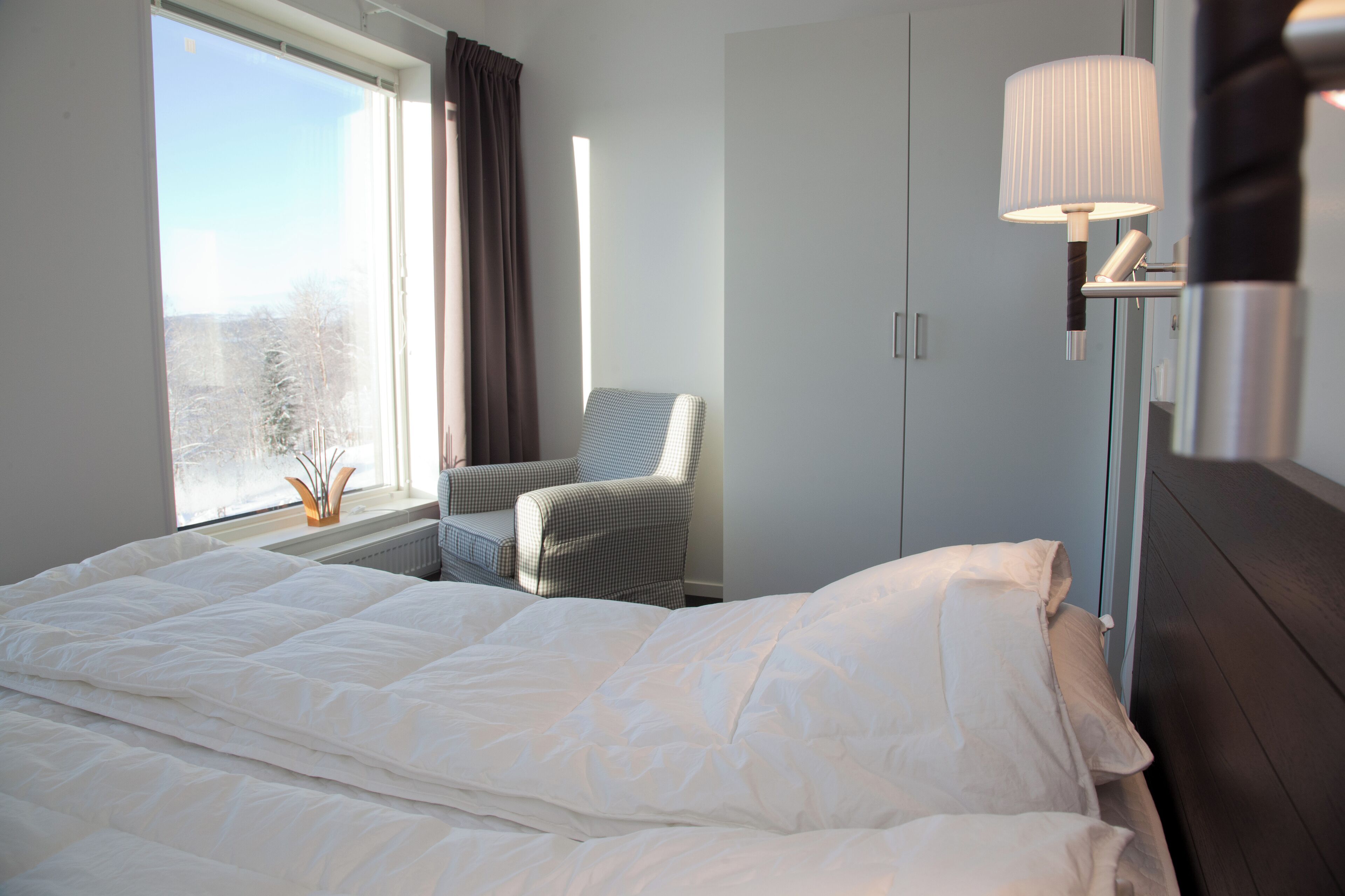 Una camera d'albergo con un letto grande, una sedia, una scrivania e una lampada.