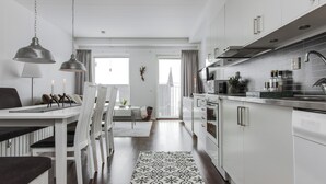 Una cocina moderna con armarios blancos, electrodomésticos de acero inoxidable y una alfombra estampada.